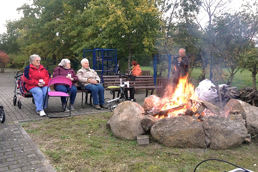 Lagerfeuer im Betreuten Wohnen Luckenwalde, drei Damen sitzen gemützlich am Lagerfeuer