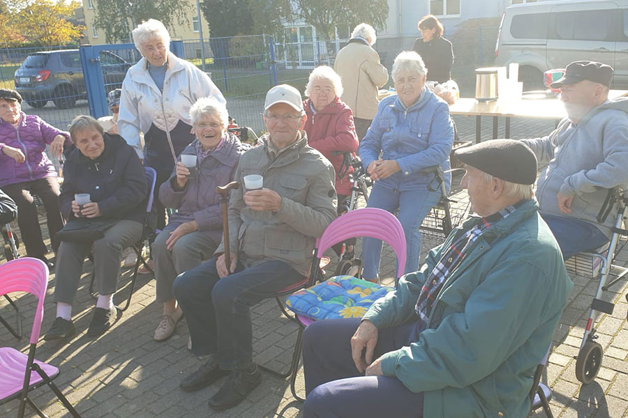 Eine Seniorinnengrupe genießt bei warmen Getränken die Sonne im Hof des Betreuten Wohnen Elsthal 